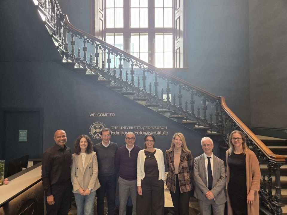 GENIUS Doctoral Network beneficiaries standing in a line in front of The University of Edinburgh logo at Edinburgh Future Institute